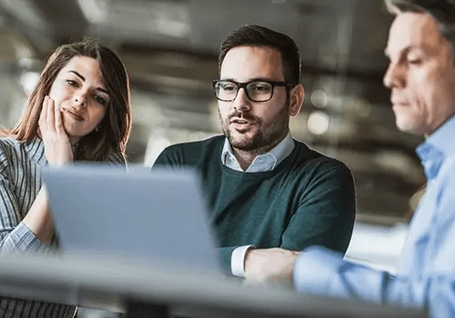 Three persons looking into a laptop screen