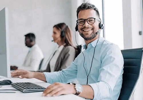 A smiling person with a headset on a computer