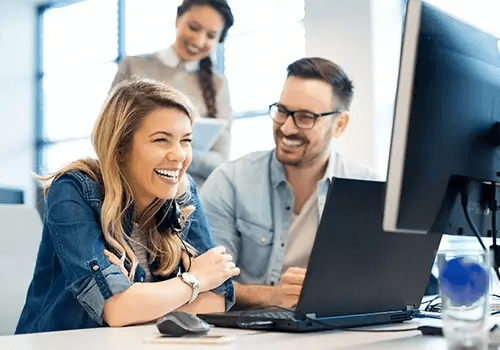 People laughing in front of a computer