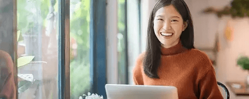 Woman smiling behind a laptop