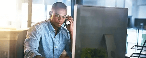 A person talking on the phone and looking at a computer screen